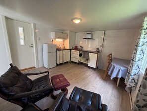 A compact living space with a kitchenette, a dining area, and a seating area with a sofa and armchair. - Lunheim Accomodation (Stranda)