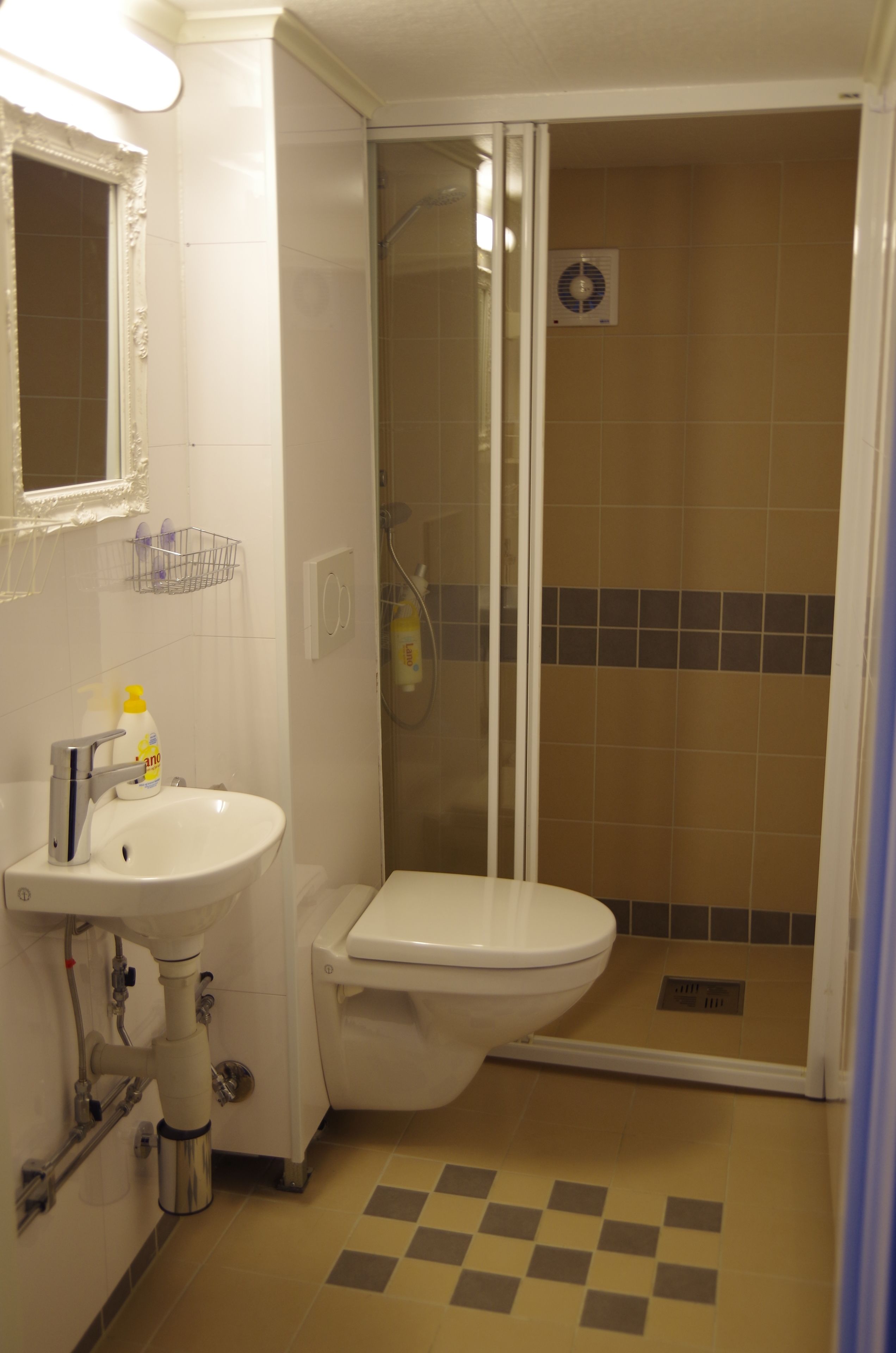 Un baño con lavamanos, inodoro y ducha con mampara de vidrio.