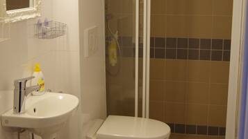 Un baño con lavamanos, inodoro y ducha con mampara de vidrio.