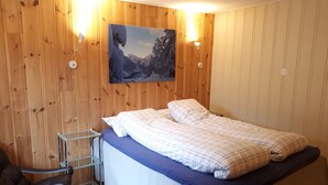 A bedroom with a bed, a chair, and a painting on the wall. - Lunheim Accomodation (Stranda)
