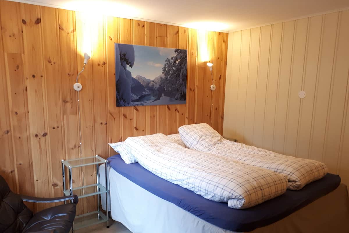 A bedroom with a bed, a chair, and a painting on the wall.