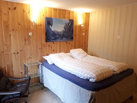 Un dormitorio con una cama, una silla y un cuadro en la pared.
