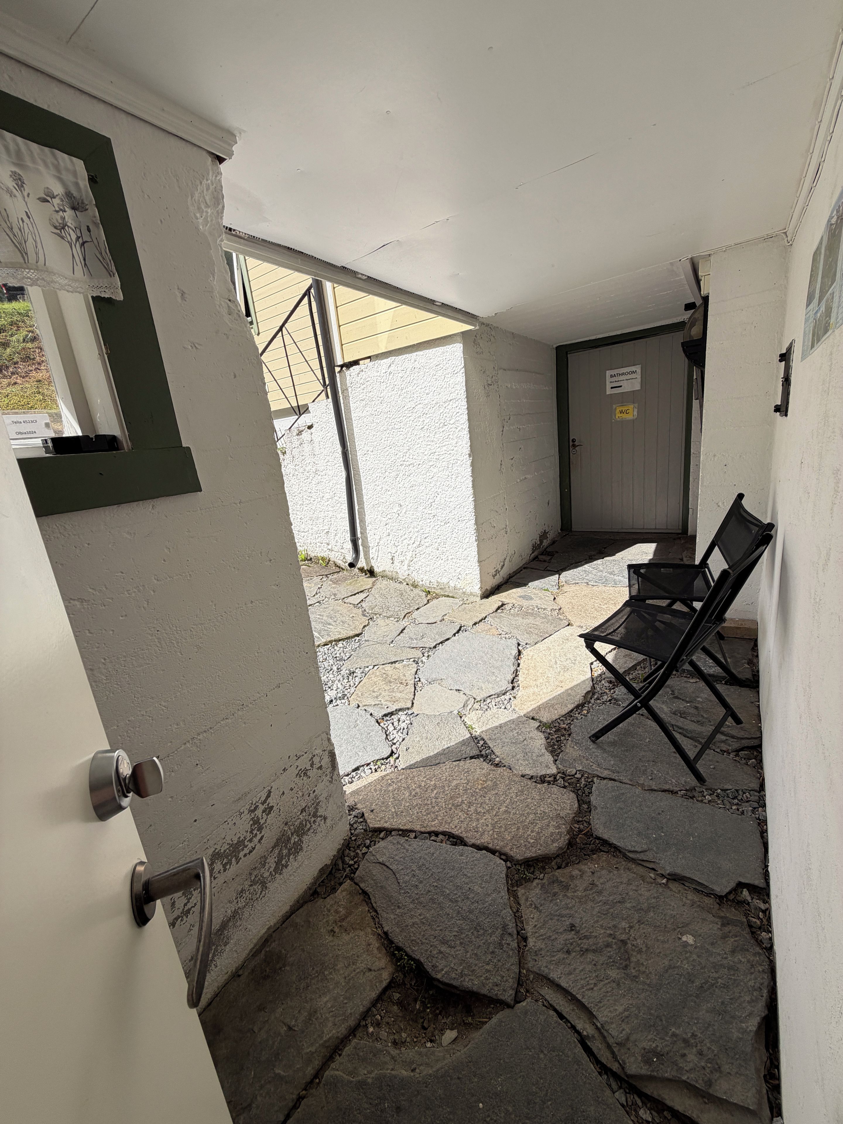 A stone-floored patio with a door leading to a bathroom.