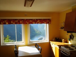 Una cocina con vistas a un paisaje montañoso a través de dos ventanas, una mesa con sillas y una estufa.