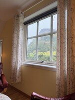 Una habitación con un ventanal grande, un sillón de cuero y vistas a un paisaje montañoso.