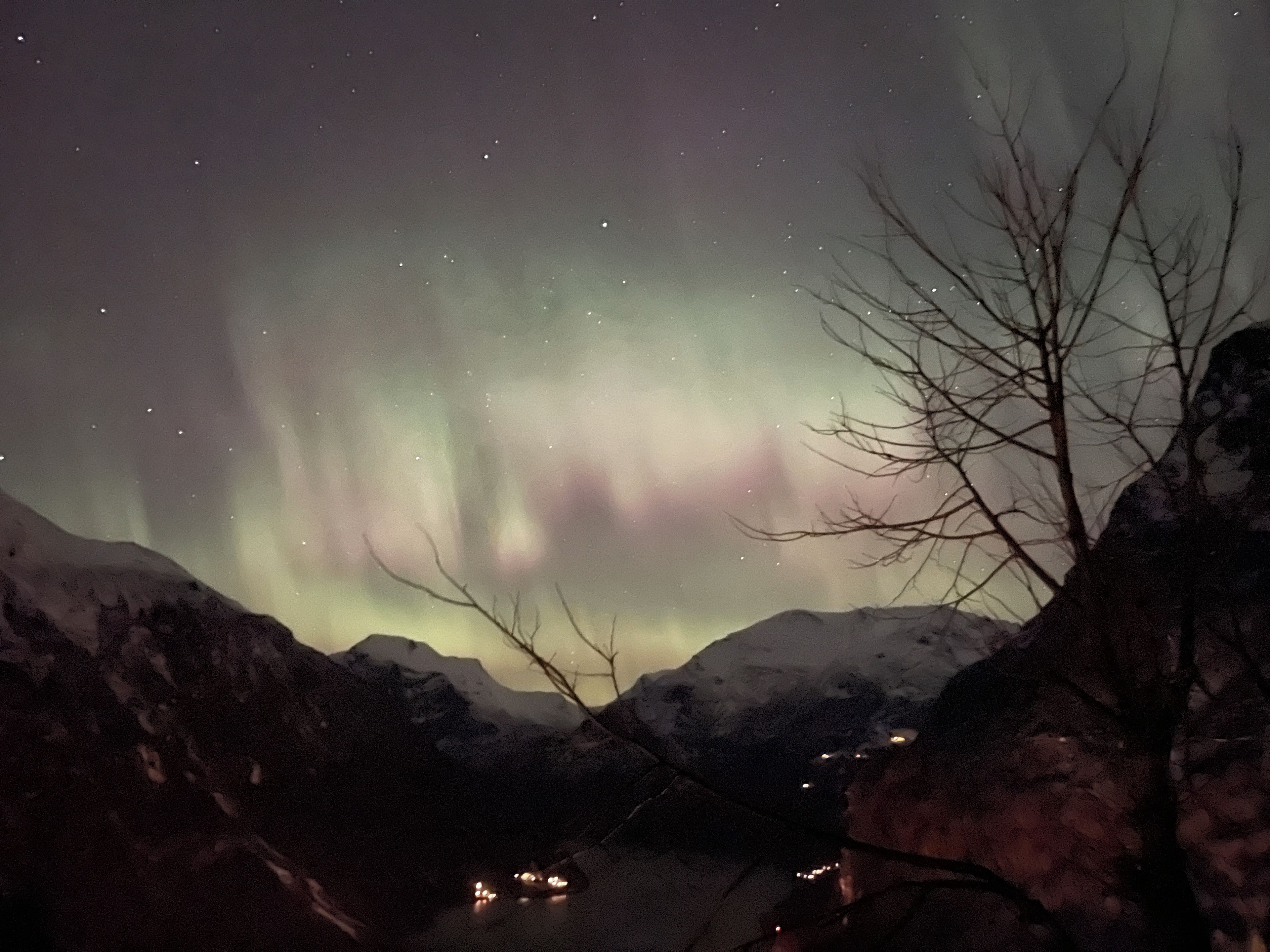 A night scene with the aurora borealis over a mountainous landscape.