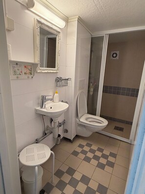 A bathroom with a sink, toilet, and shower. - Lunheim Accomodation (Stranda)