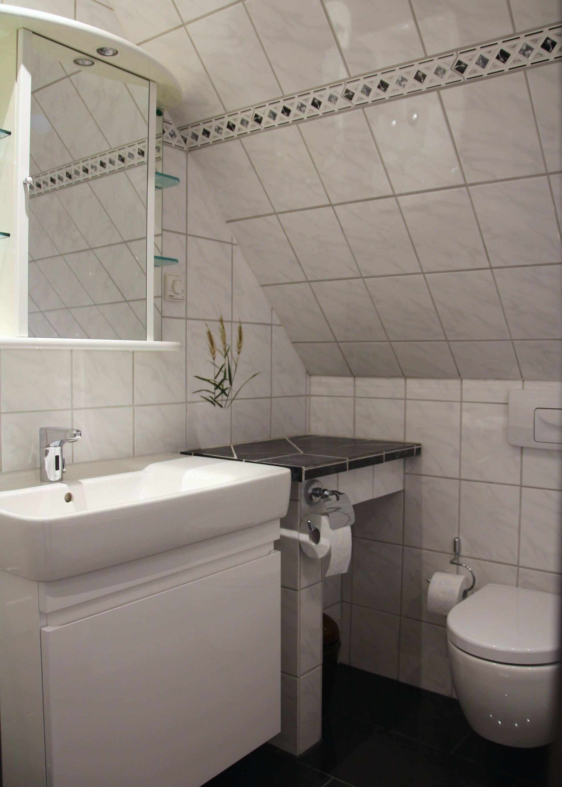 A bathroom with a white sink, mirror, and toilet.