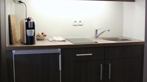 A compact kitchen with dark wood cabinets, a small countertop, a coffee maker, and a sink.