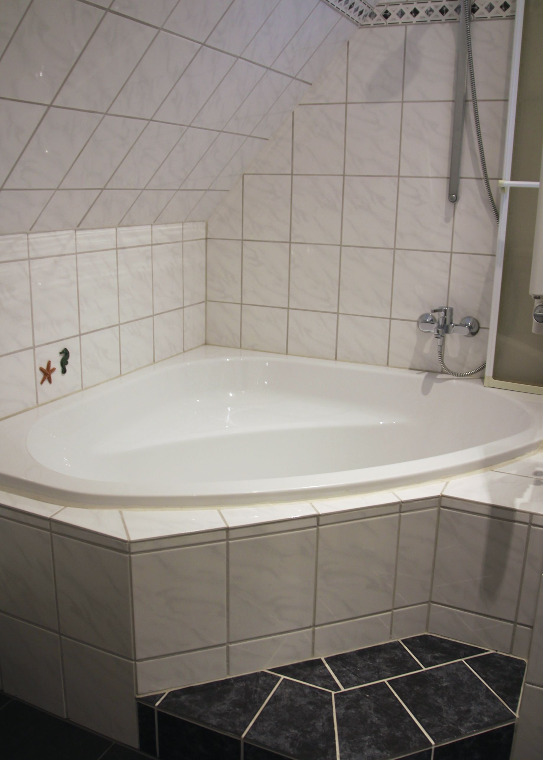A bathroom with a freestanding bathtub, tiled walls, and a shower area.