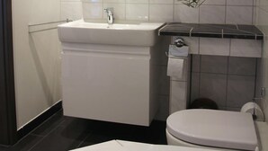 A modern bathroom with a white sink, mirror, and toilet.