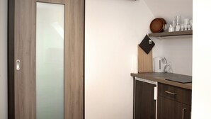 A modern kitchen with a sliding door, a coffee maker, and a shelf with kitchenware.