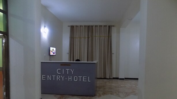 Ein Empfangsbereich mit einer Rezeption, auf der “CITY ENTRY-HOTEL” steht.