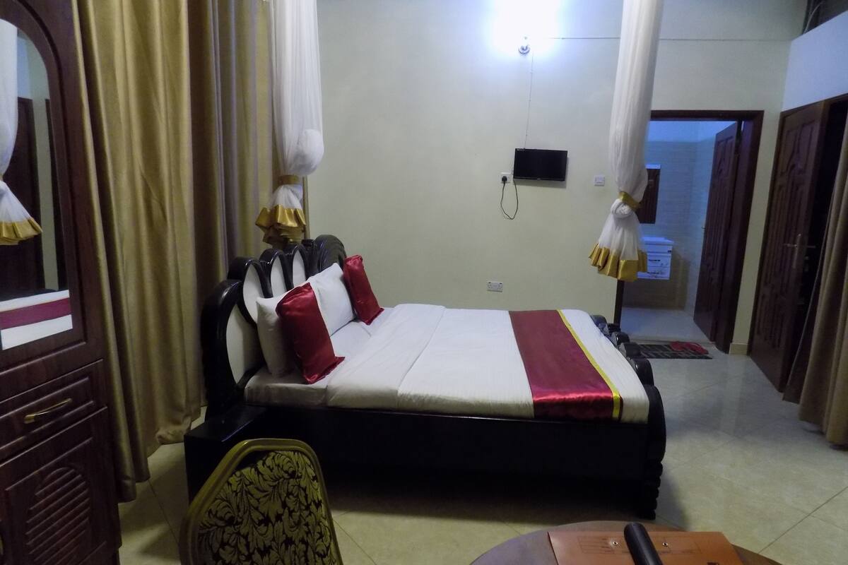 Una habitación de hotel con cama, una silla, un escritorio y televisor.
