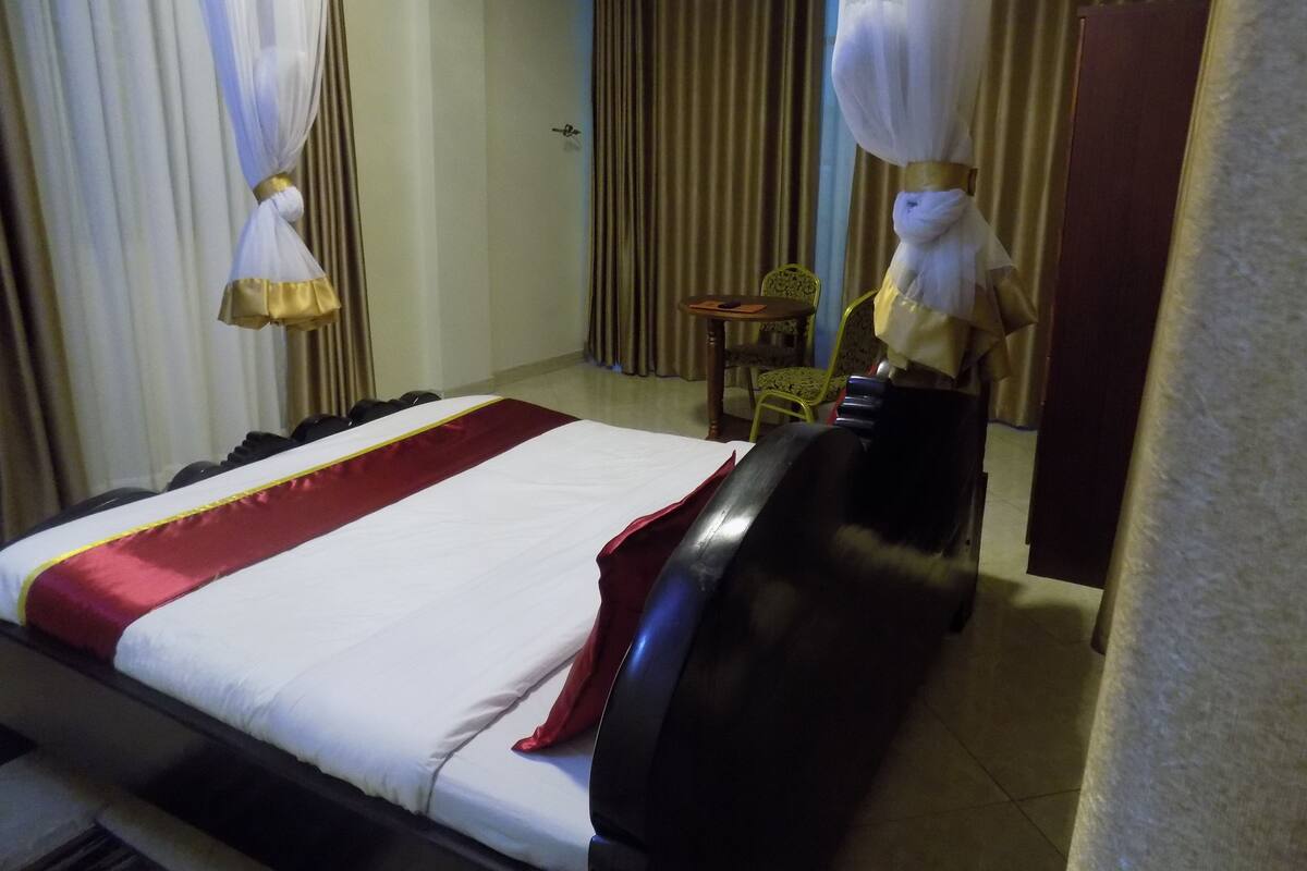 Una habitación de hotel con una cama, una silla, una mesa y un armario.