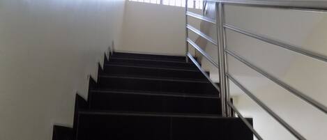 A staircase with metal railings leading up to a window with blinds.