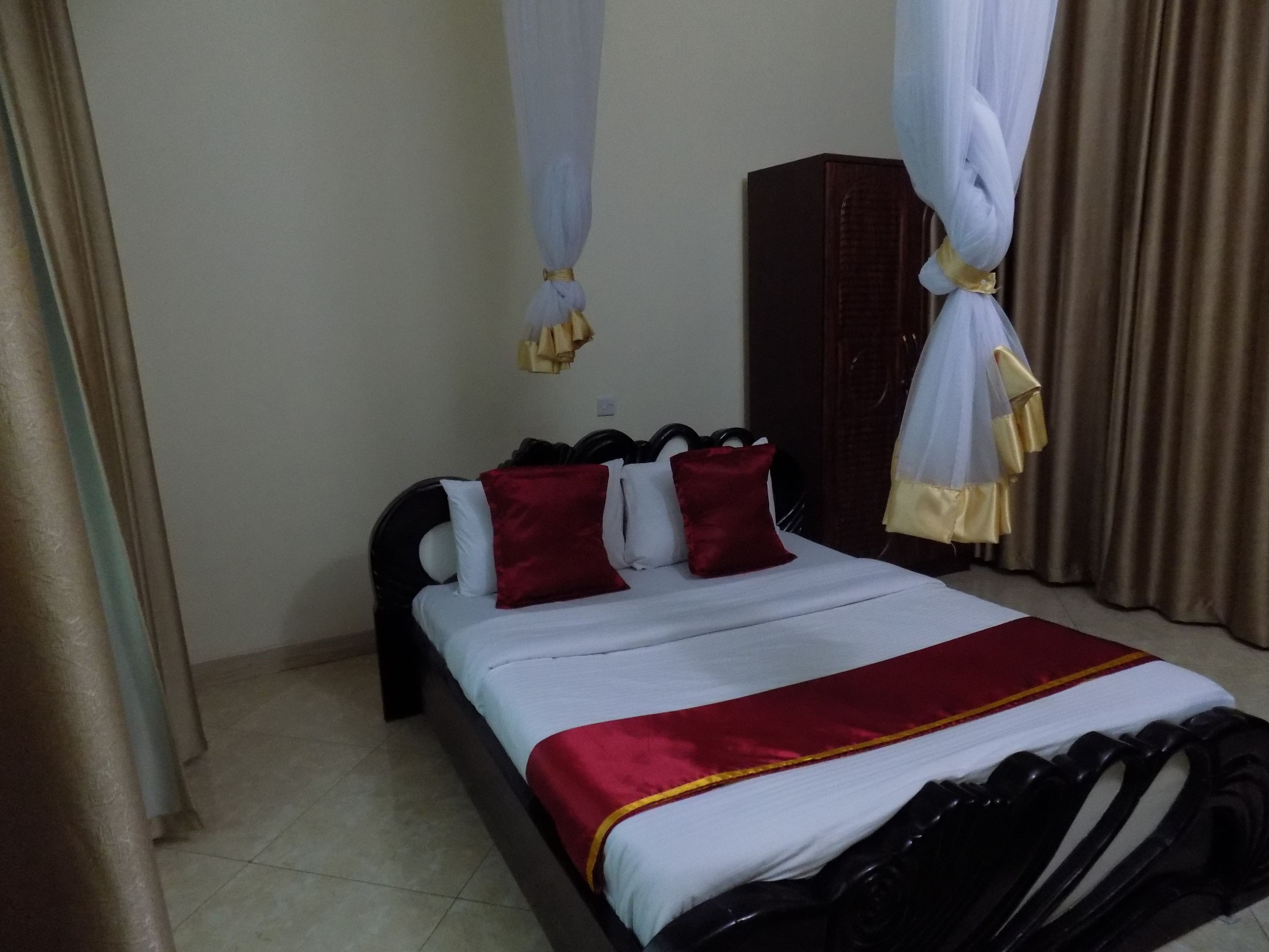 Una habitación de hotel con cama, armario y cortina.
