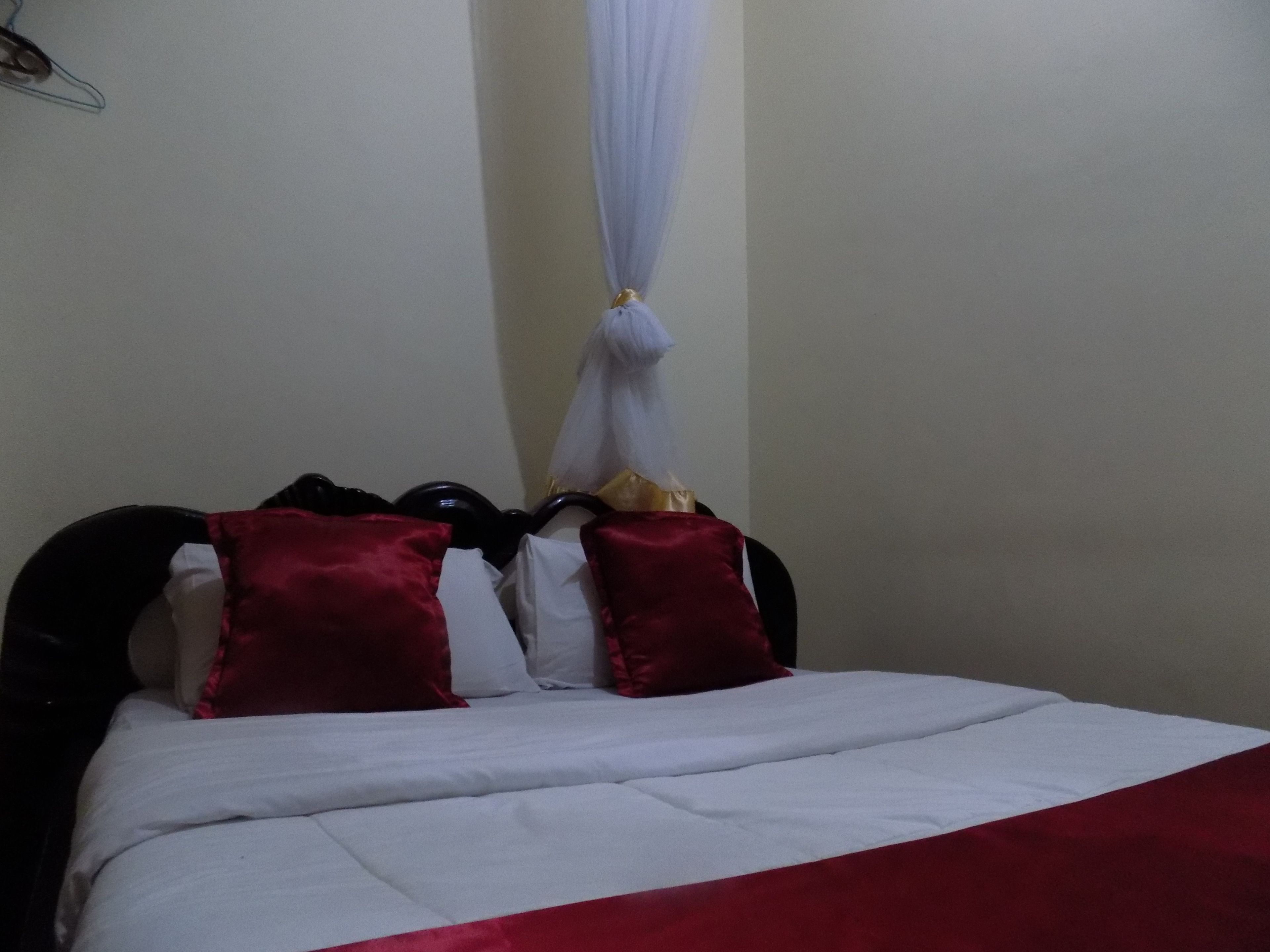 A bed with a white and red bedspread, two red pillows, and a white canopy.