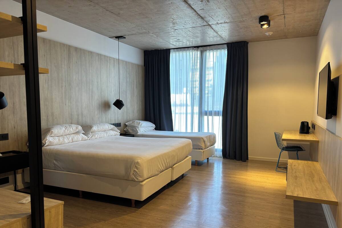 A modern hotel room with a large bed, a desk, and a chair.