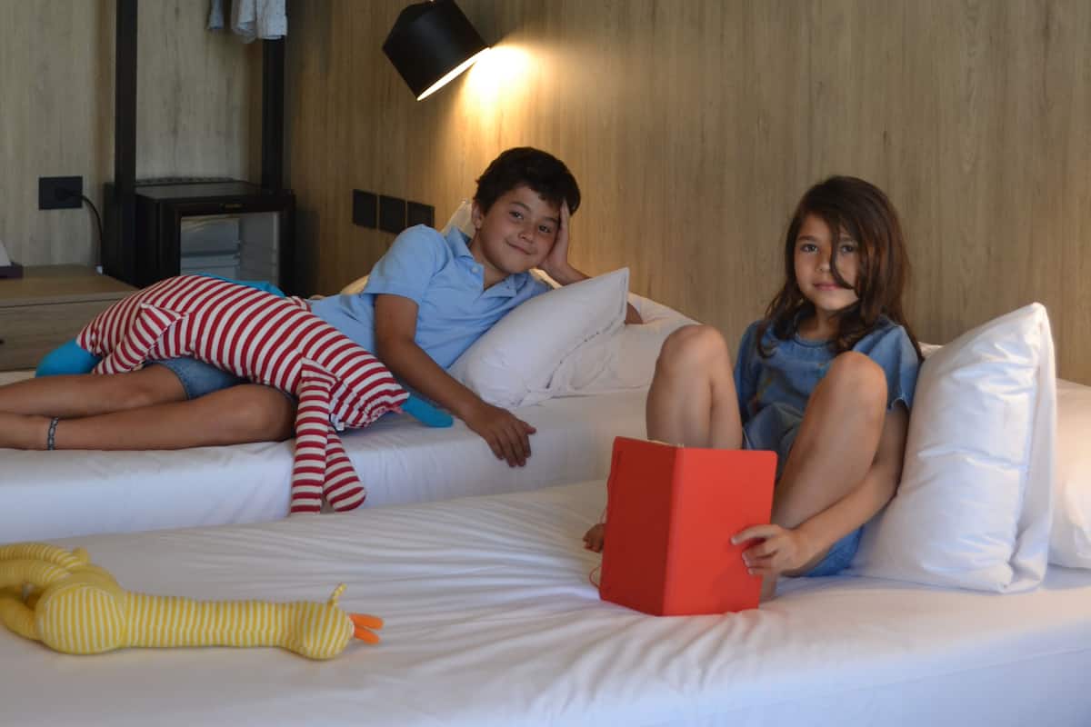 Two children on a bed with a lamp in the background.
