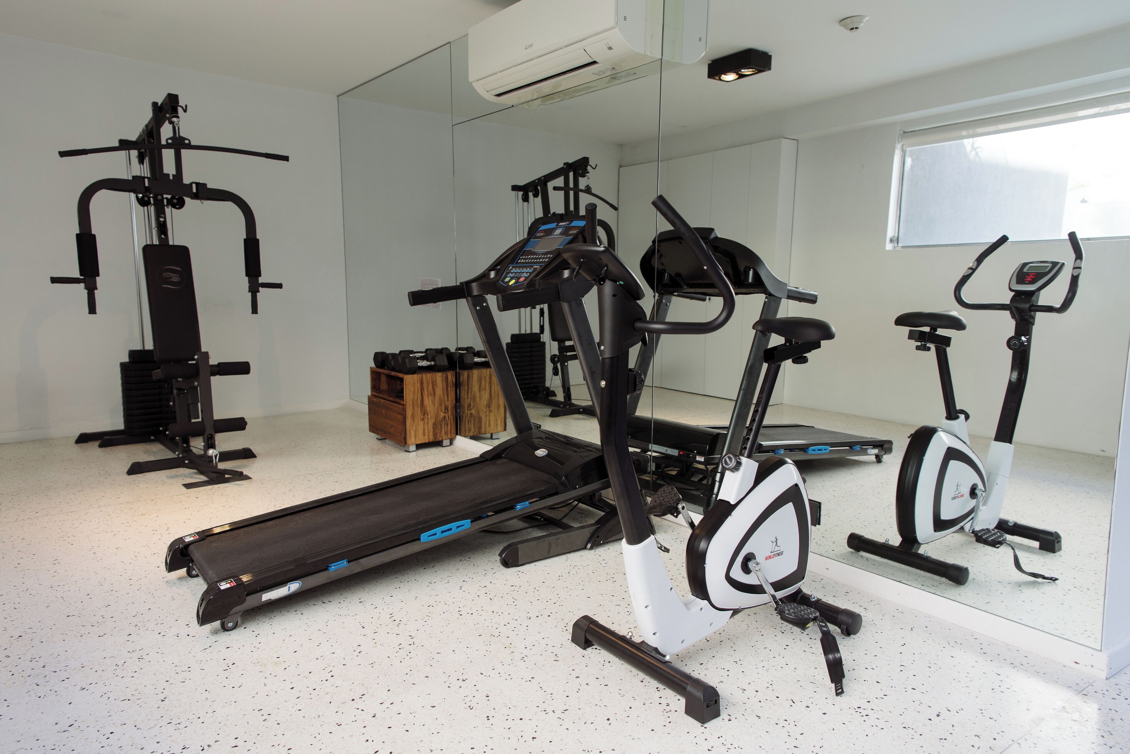 A gym with a treadmill, elliptical, and stationary bike.