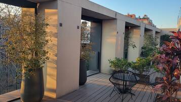 Una terraza moderna al aire libre con suelo de madera, plantas en macetas y una zona de estar.