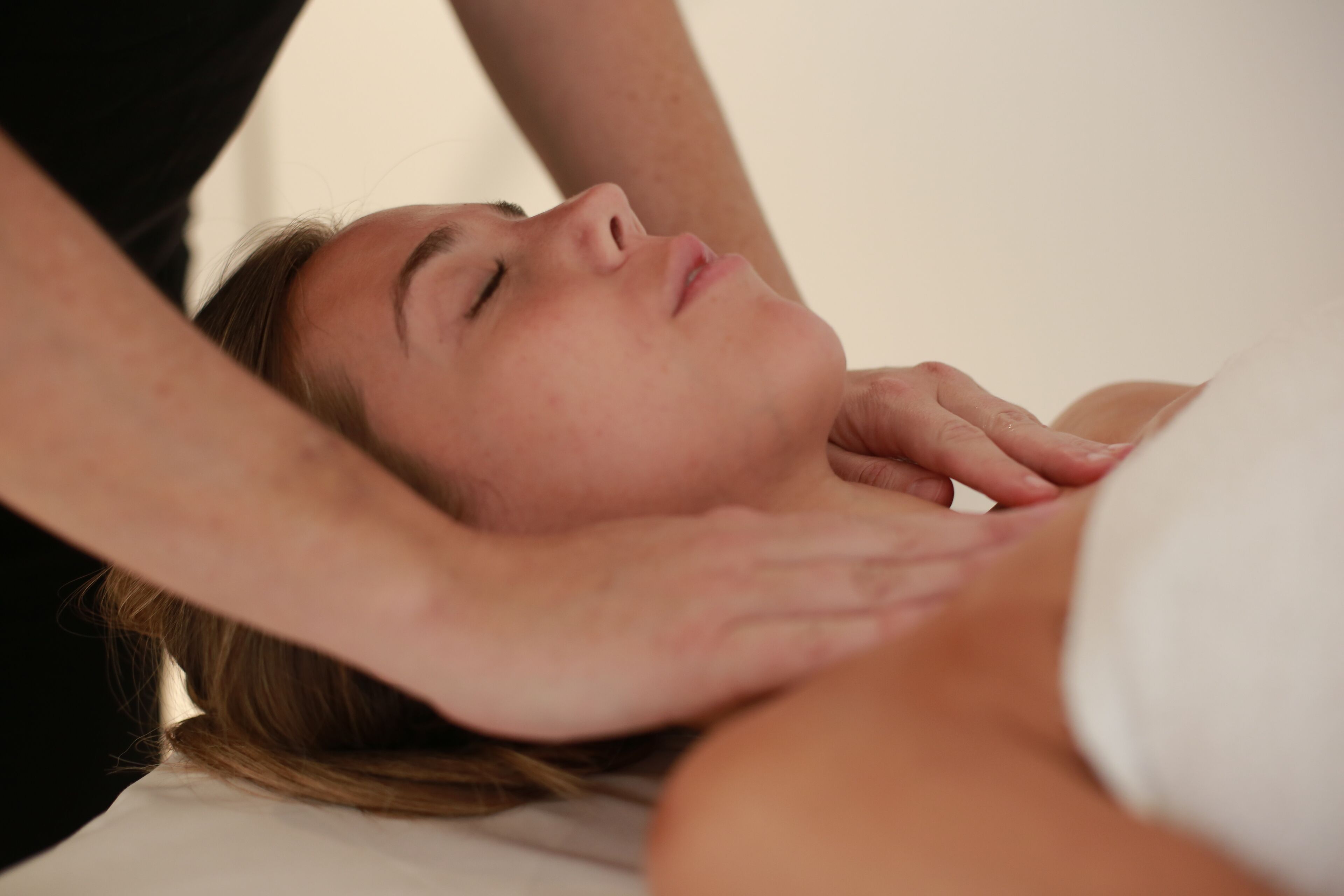 A person lying on a bed receiving a massage.
