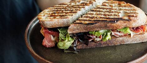 Una persona sosteniendo un sándwich a la parrilla en un plato de cerámica.