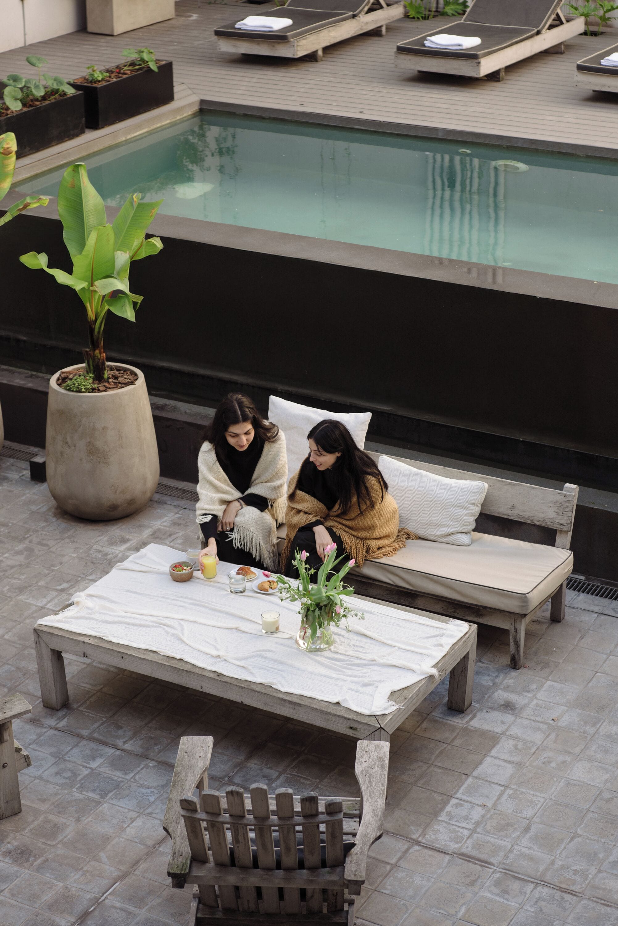 Un espace piscine sur le toit, avec des chaises longues et un banc pour s’asseoir.