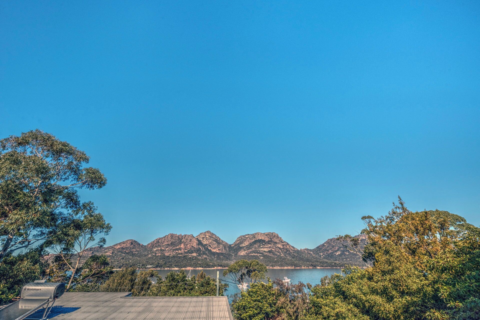 A view of a lake with mountains in the background and a wooden deck in the foreground.