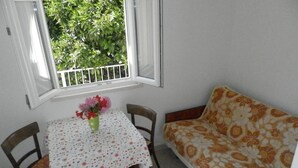Un petit coin repas avec une table recouverte d’une nappe à motifs floraux, un vase rempli de fleurs et un canapé agrémenté d’un coussin à motifs floraux.