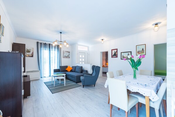 Uma sala de estar moderna com sofá, poltrona, mesa de jantar e vista para a cidade.