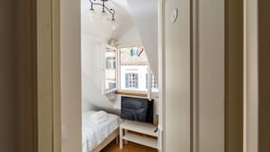 Un dormitorio con cama, televisor y ventana con vistas a un edificio.