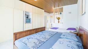 A bedroom with a wooden ceiling, a bed with patterned bedding, a TV, and a mirror. - Apartments Veve - Superior Studio Apartment with Terrace Sea View (Postira)