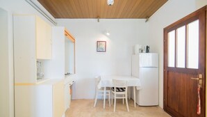 A compact kitchen with a white table, chairs, and a refrigerator. - Apartments Veve - Superior Studio Apartment with Terrace Sea View (Postira)