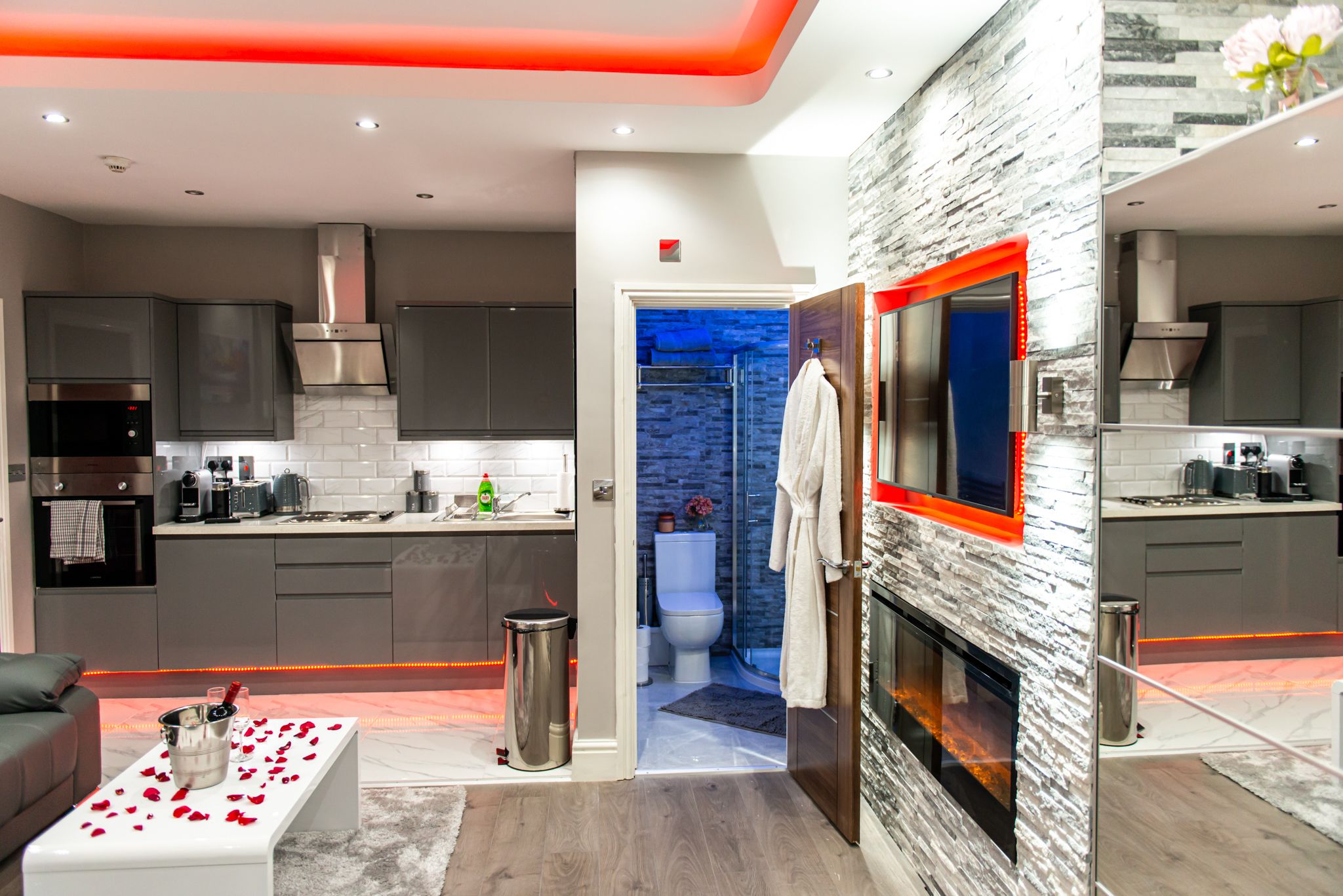 A modern kitchen with grey cabinets, a stainless steel range hood, and a built-in oven.
