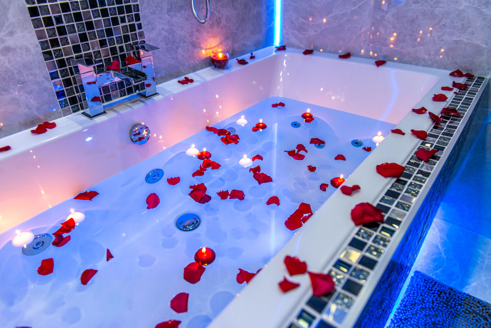 Eine Badewanne mit Rosenblättern und Kerzen.