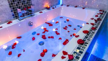 Eine Badewanne mit Rosenblättern und Kerzen.