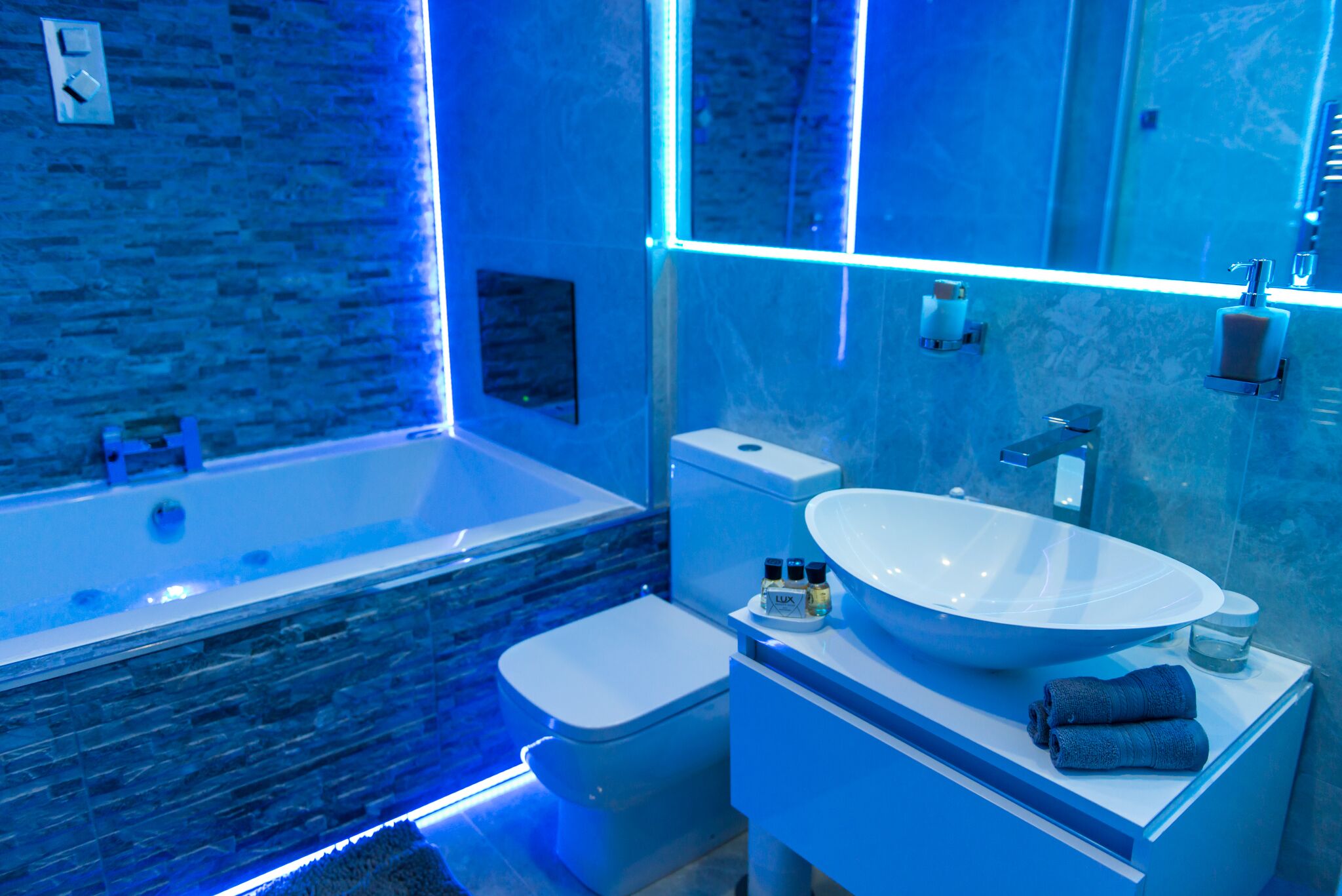 A modern bathroom with a large bathtub, a white sink, and a toilet.