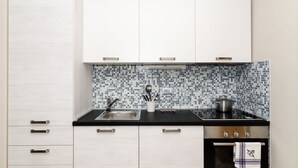 Et moderne køkken med hvide skabe, en sort bordplade og et flisebeklædt backsplash.