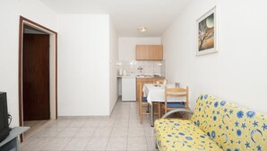 Un espacio habitable compacto con kitchenette, comedor y sofá.