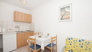 Una cocina compacta con una mesa de comedor para dos, un refrigerador pequeño y armarios de madera.