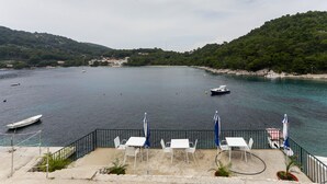 Eine Küstenterrasse mit Außenplätzen und Blick auf das Meer sowie Boote.