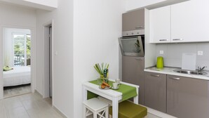 Eine kleine Küche mit Essbereich, darunter ein Tisch mit grüner Tischdecke, eine Bank und ein kleiner Backofen.