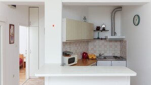 Een kleine keuken met een magnetron, broodrooster en waterkoker op het aanrecht, een spoelbak en een klok aan de muur.