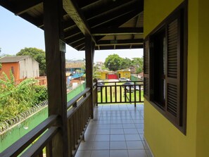 A balcony with a tiled floor and a view of a residential area with houses and greenery. - Pousada Nusa Dua Maresias (São Sebastião)