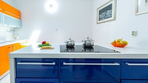 Eine moderne Küche mit blauen und orangefarbenen Schränken, einer weißen Arbeitsplatte und zwei Edelstahltöpfen.