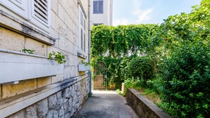 A narrow alleyway with a stone wall on one side and a building with a white facade on the other.