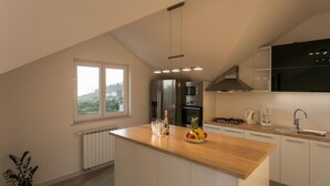 Una cocina moderna con una isla central, electrodomésticos de acero inoxidable y vistas al exterior.