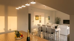 Un comedor moderno con una mesa de madera, sillas blancas y una botella de champán.